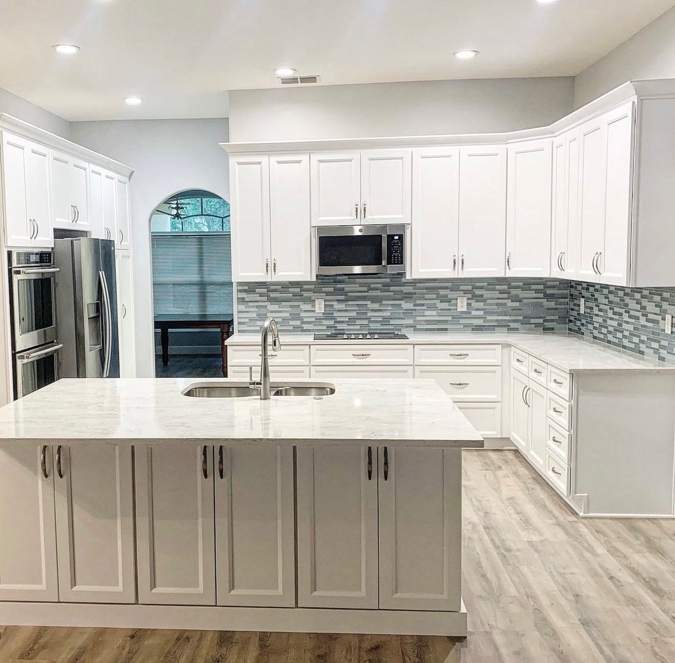 Bright white kitchen with marble island and gray mosaic backsplash installed by Dreamstone Surfaces